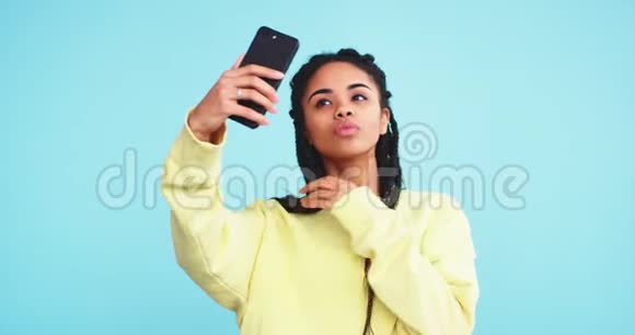 自拍的时候一位年轻漂亮的非洲女士在一个有蓝色背景墙的工作室里戴着可怕的帽子她在拍照视频的预览图