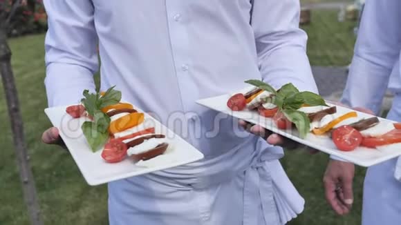 服务员端着两个盘子里面有卡培沙拉和活动小吃视频的预览图