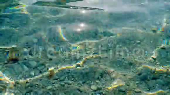 特写镜头在爱琴海清澈的水面下可以看到小的多色鹅卵石阳光光线反射视频的预览图