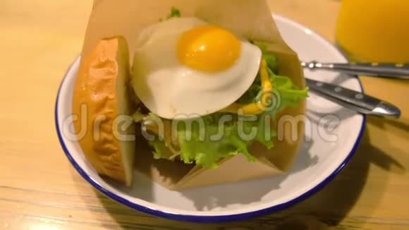 大汉堡有鸡蛋和新鲜蔬菜用叉子和刀子放在盘子里视频的预览图