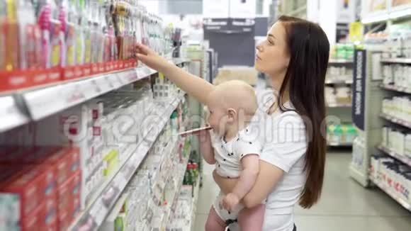 漂亮的女人带着小儿子在超市购物年轻的妈妈在市场上为家人选择牙刷视频的预览图