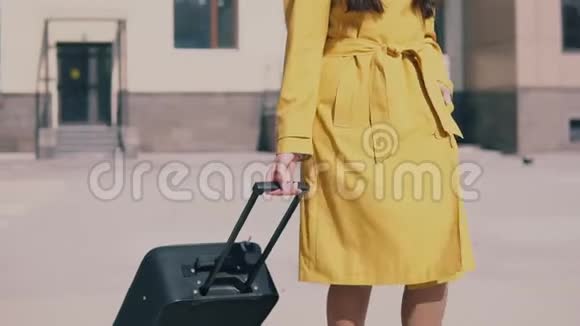 一位美丽的女士身穿黄色斗篷戴着眼镜留着一头深色长发带着行李视频的预览图