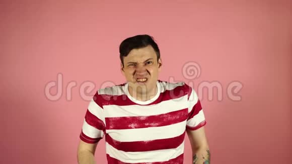 一个困惑的年轻人耸耸肩肩膀孤立在粉红色的背景上视频的预览图