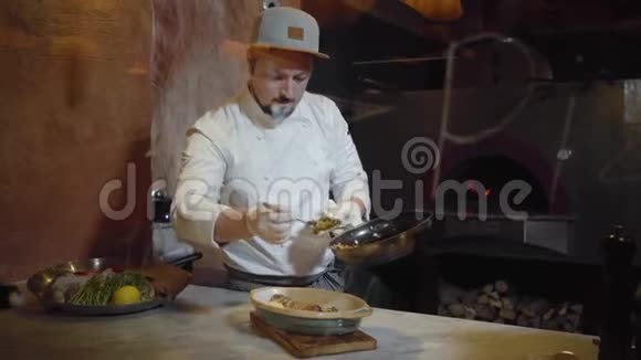 厨师穿着白色制服把切成小块蒸蔬菜放在煮熟的鱼上躺在深深的盘子里视频的预览图