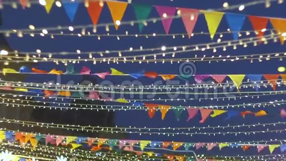 许多五颜六色的小旗在风中摇曳电光花环装饰着城市假日装饰品视频的预览图
