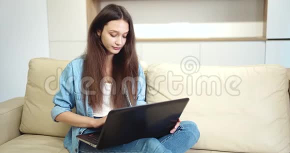 年轻女士在空平间打手提电脑视频的预览图