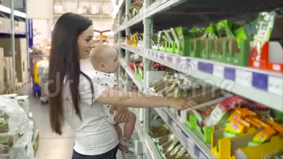 美丽的女人带着小儿子在超市购物年轻的母亲在市场上为家人选择香料视频的预览图
