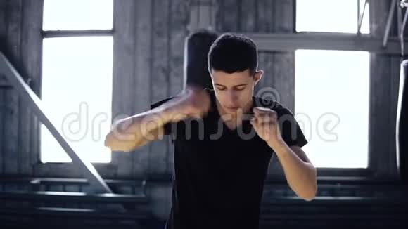 男拳手伸手臂穿黑色t恤年轻运动员在拳击馆热身伸展手臂打开窗户视频的预览图