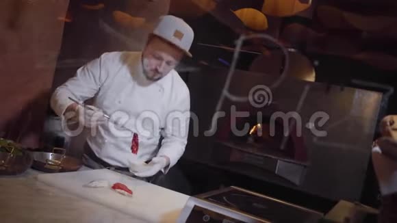 专业厨师穿着白色夹克橡胶厨师在餐厅的厨房里用红鱼做三明治这就是视频的预览图