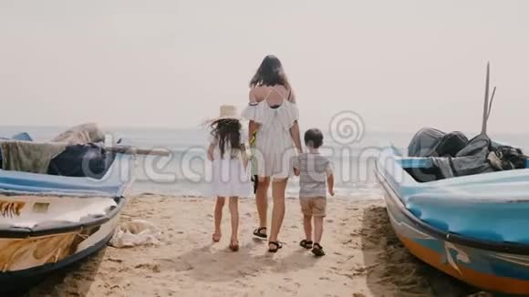 镜头跟随着幸福的年轻女子孩子们在船上漫步走向美丽的阳光沙滩视频的预览图