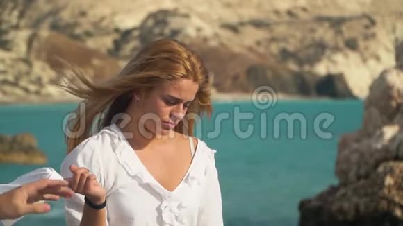 悲伤的金发女人站在海边手里拿着白衬衫男人从女孩手拿衣服两个人在洛基休息视频的预览图
