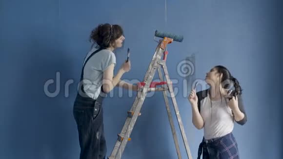 两个年轻漂亮的女人一边唱歌一边跳舞一边画自己的公寓视频的预览图
