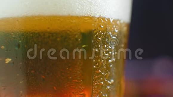 从一杯啤酒上掉了一滴水在一杯冰冷的啤酒上流汗一滴滴在玻璃上视频的预览图