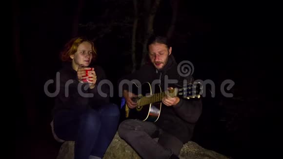 浪漫情侣在篝火旁弹吉他视频的预览图