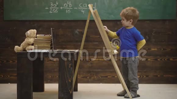 可爱的蹒跚学步的男孩在木制背景上画黑板小艺术家在木制背景上画画概念视频的预览图