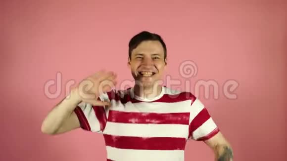 男人摆了摆手在粉红色的背景上微笑视频的预览图