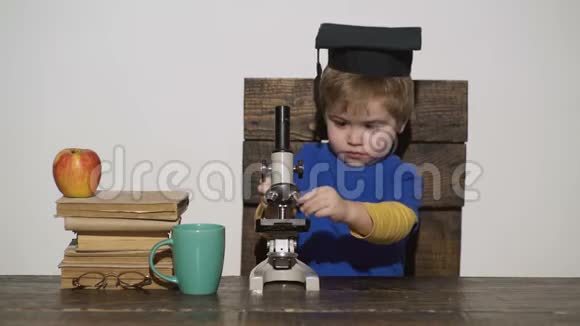孩子在显微镜里看Wunderkind概念聪明的小男孩用显微镜工作的科学家孩子笔记本电脑视频的预览图