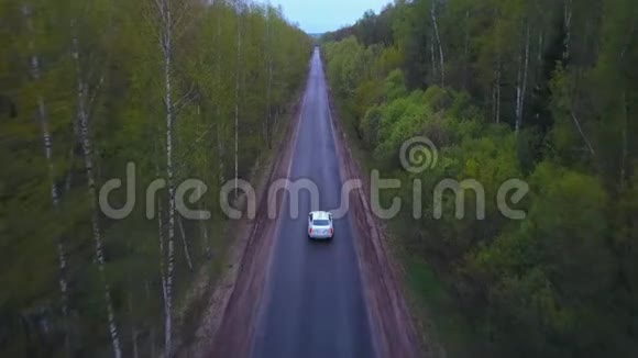 从无人驾驶飞机上俯瞰白色高档汽车骑在孤独的道路上视频的预览图