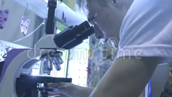 在实验室工作的生命科学家一个学生正在看显微镜他研究周围的世界视频的预览图