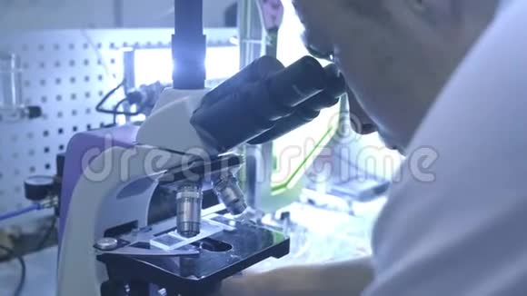 在实验室工作的生命科学家一个学生正在看显微镜他研究周围的世界视频的预览图