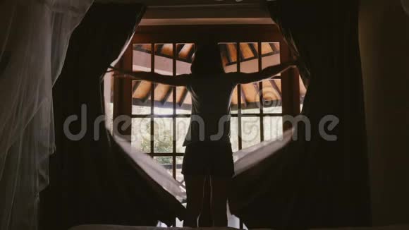后景幸福年轻的旅游妇女打开小屋的窗帘和窗户门走出去在阳光明媚的露台伸展视频的预览图