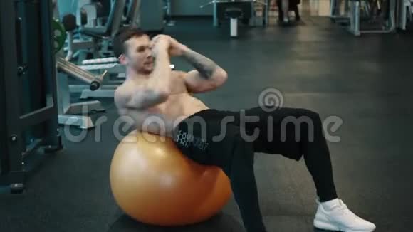 年轻的肌肉男用运动球训练腹部肌肉视频的预览图