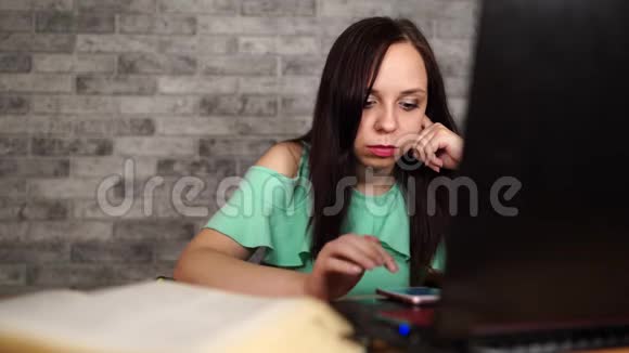 女人坐着电脑女人在办公室里用智能手机女人在电话里写信息视频的预览图