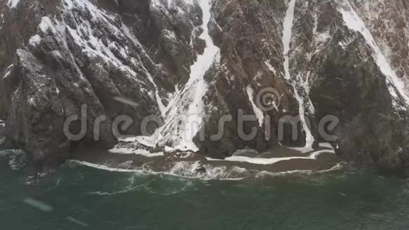 当无人驾驶飞机下雪时向岩石和海岸射击视频的预览图