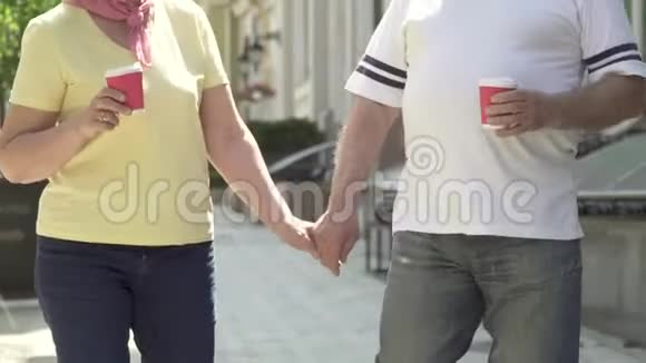 在城里散步的老夫妇牵着手喝咖啡视频的预览图