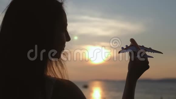 在海上日落时女孩手里拿着飞机模型的剪影思想观念视频的预览图