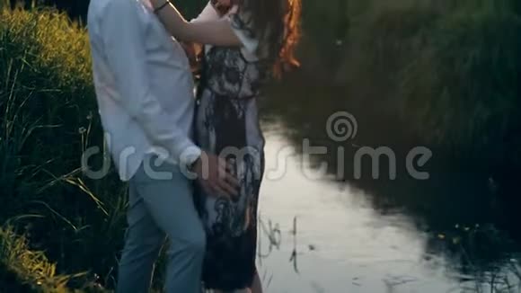 日落时在河边的公园里的一对夫妇爱情感情亲吻视频的预览图