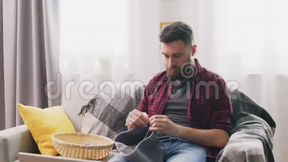放大坐在沙发上和在家编织的男人视频的预览图
