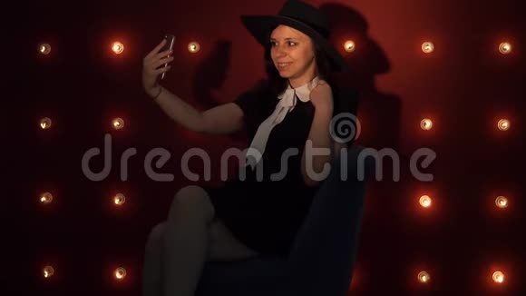 女士坐在椅子上在智能手机上自拍一个穿着黑色裙子的美女在拍照视频的预览图