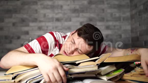 一个学生带着许多准备考试的书在书上睡着了视频的预览图