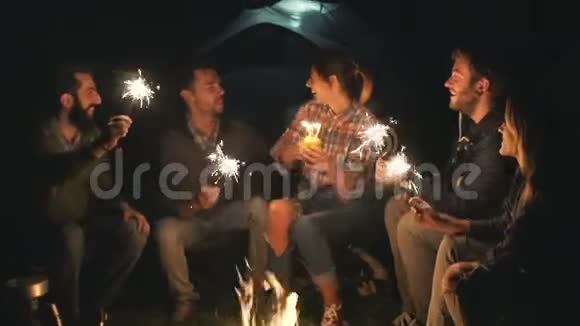 这对夫妇在篝火前的树林里和朋友们一起庆祝野餐视频的预览图