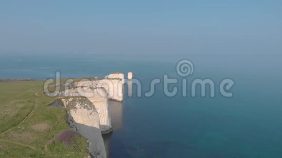 在一片令人惊叹的朦胧中古老的哈利岩石在美丽的巨大的白色悬崖和晶莹的蓝色水面上的空中后景视频的预览图
