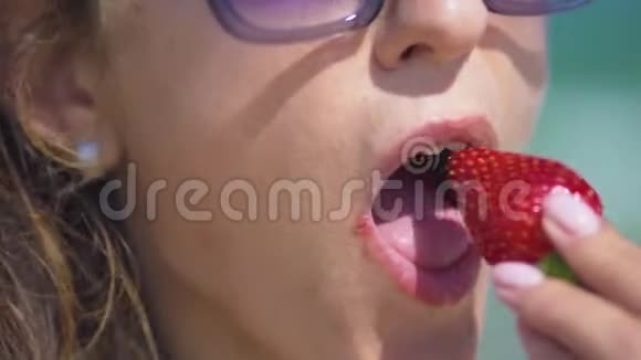 阳光明媚的夏天女人在海边吃草莓特写镜头视频的预览图