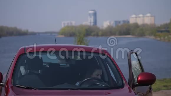女孩坐在一辆红色的车里打开门爬出车外出示钥匙4K慢慢视频的预览图