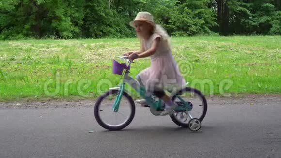 微笑可爱的女孩在公园里骑自行车平行移动射击视频的预览图