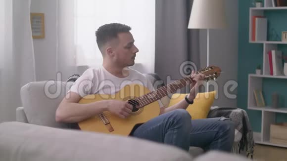 跟踪年轻人在他舒适的客厅里弹吉他视频的预览图