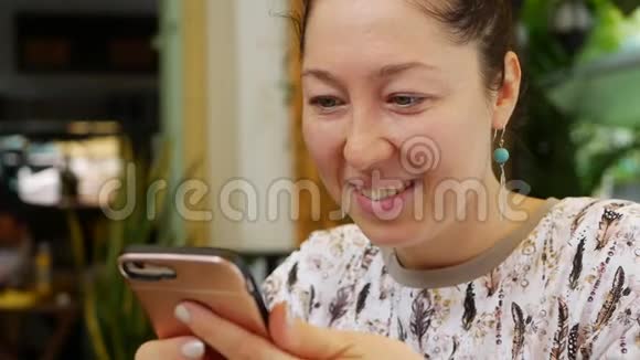 快乐女孩使用智能手机写信息聊天年轻的女人在电话里寻找信息坐在里面视频的预览图