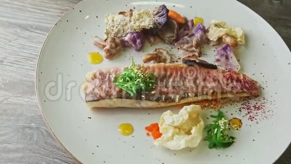 时尚装饰的烤鱼片和切好的蔬菜在盘子上旋转视频的预览图