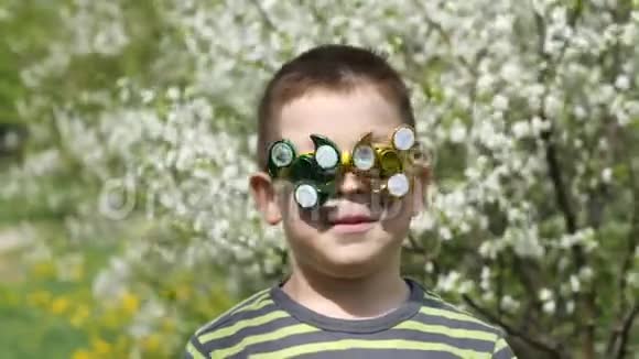 眼镜上的旋转器在旋转在街上玩得很开心一个孩子在樱花盛开的背景下视频的预览图