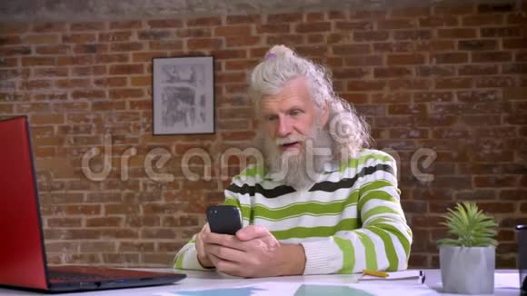 一个留着大胡子的老白头发的男人正坐在办公室里一边打着电话一边孤立无援视频的预览图