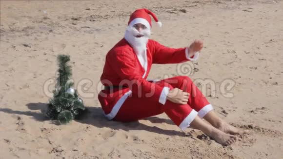 圣诞老人正坐在沙滩上迎接圣诞节的新年视频的预览图