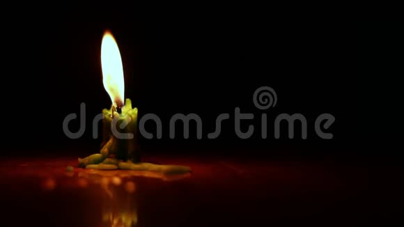 一支蜡烛在黑暗中燃烧一支美丽的蜡烛在黑暗的房间里燃烧一支温暖的绿色蜡烛在黑暗中静静地燃烧视频的预览图