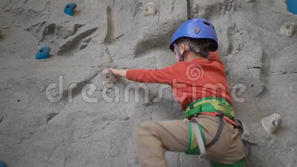 小男孩在室内的马具里爬岩壁体育生活理念视频的预览图