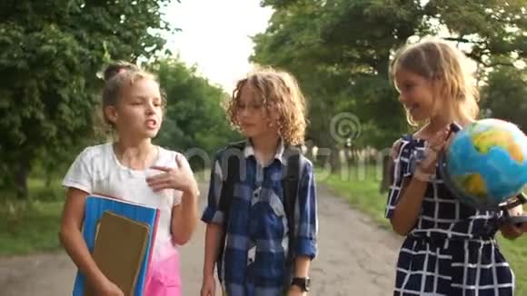 三个学生上学一个男孩和两个女孩带着圆木书和一个大地球仪上学视频的预览图