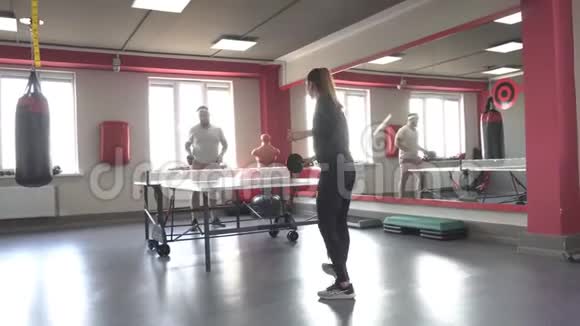 有胡子的丈夫和漂亮的妻子在现代健身房打乒乓球运动和健康视频的预览图