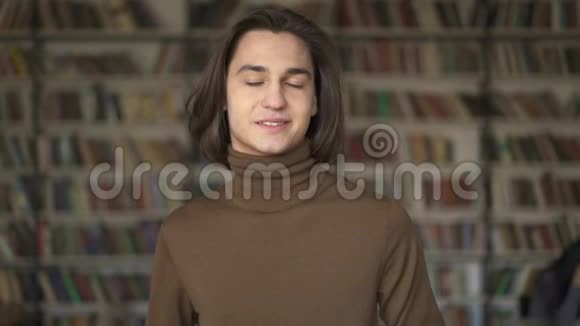 书架背景上年轻笑容可掬的学生画像视频的预览图
